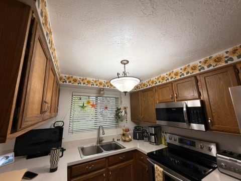 Kitchen before renovation with dark wood cabinets and floral wallpaper border