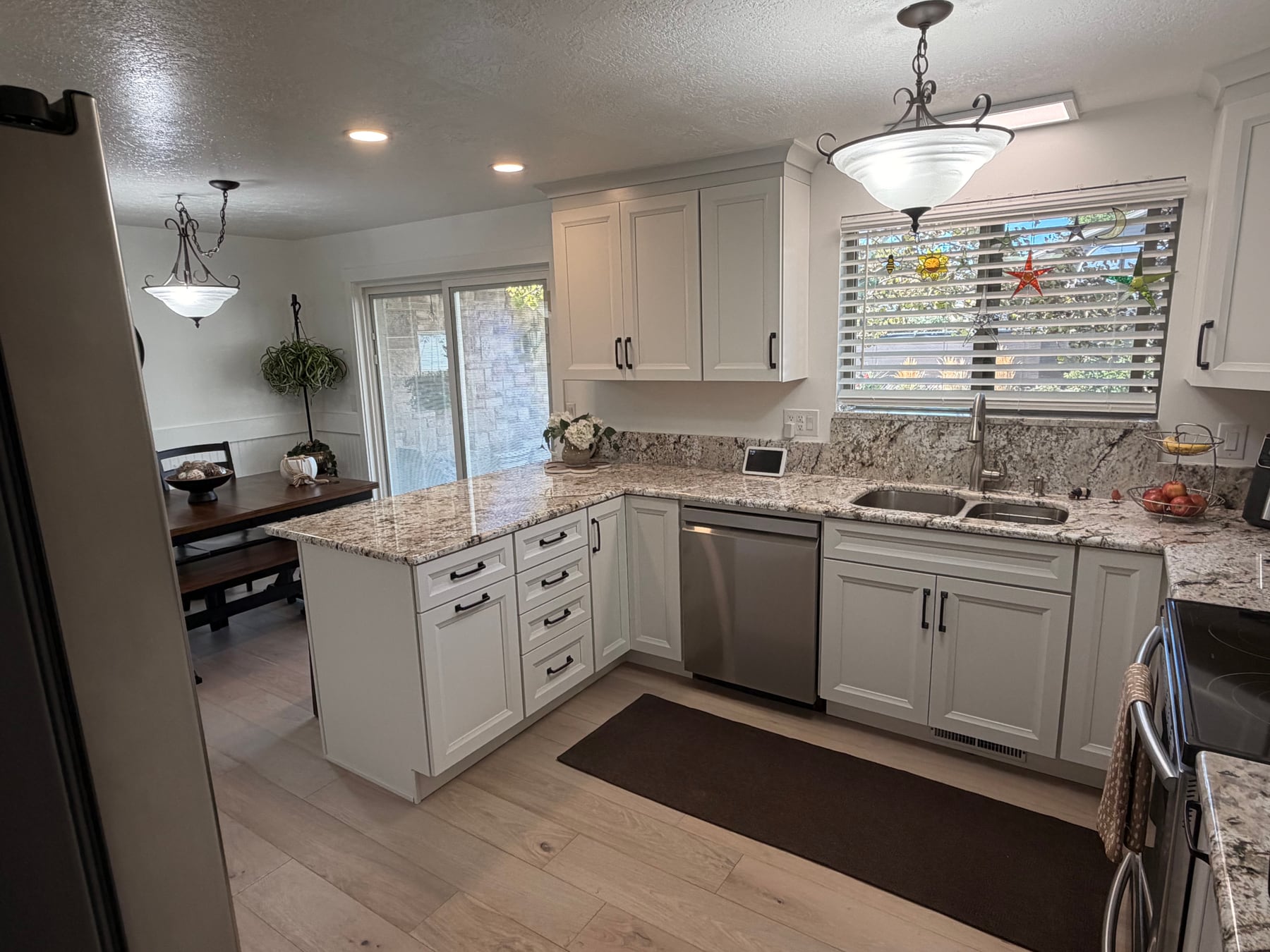 Completed bright kitchen renovation with white shaker cabinets, stone countertops, and new flooring