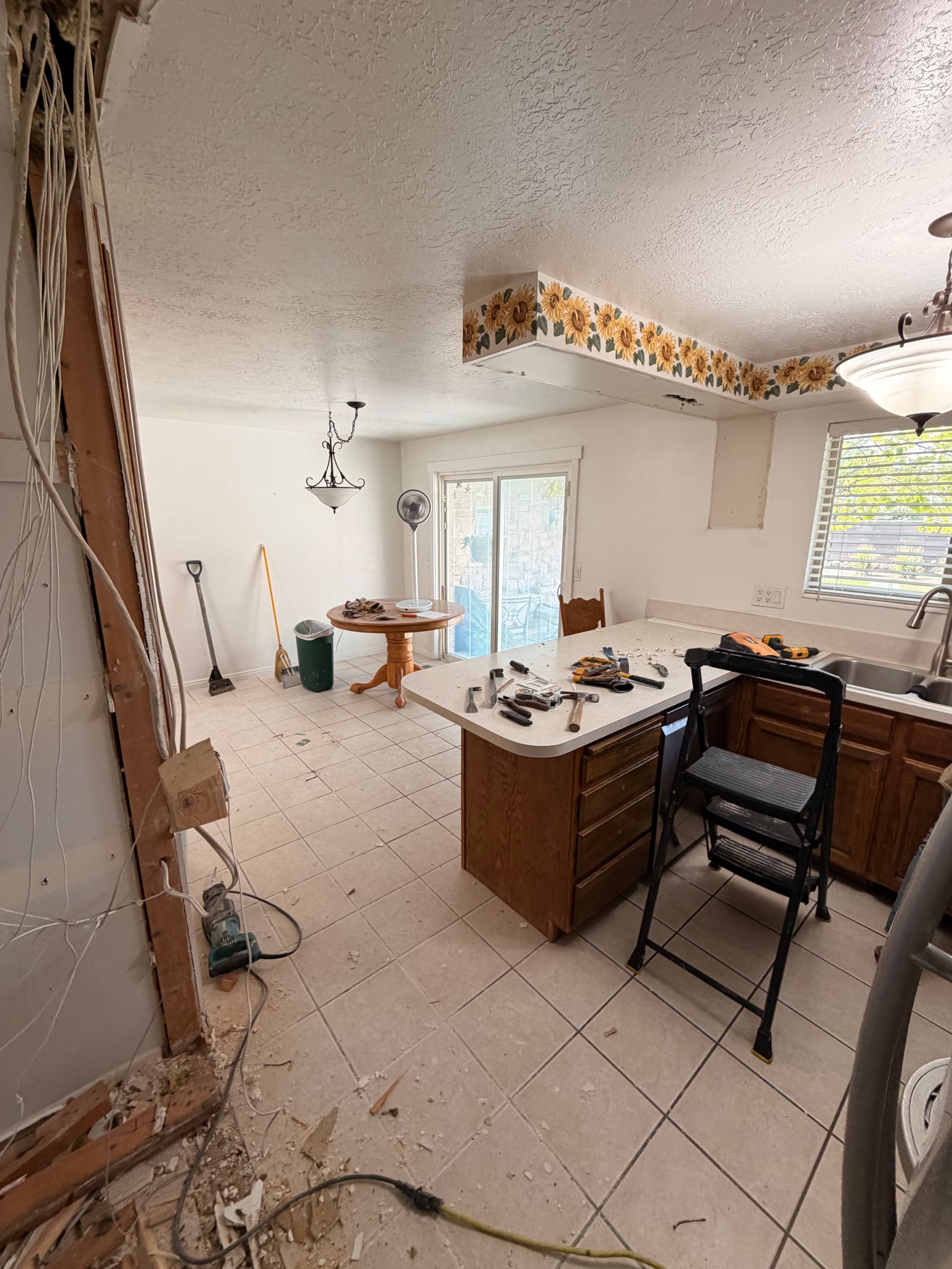 Kitchen renovation in progress with a wall opened and electrical work exposed